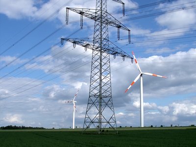 Freileitungsmast mit zwei Windrädern im Hintergrund